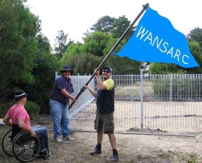 Left to right Frank VK3ZO, Mark VK3PI and Dave VK3FXDX fly the WANSARC flag
